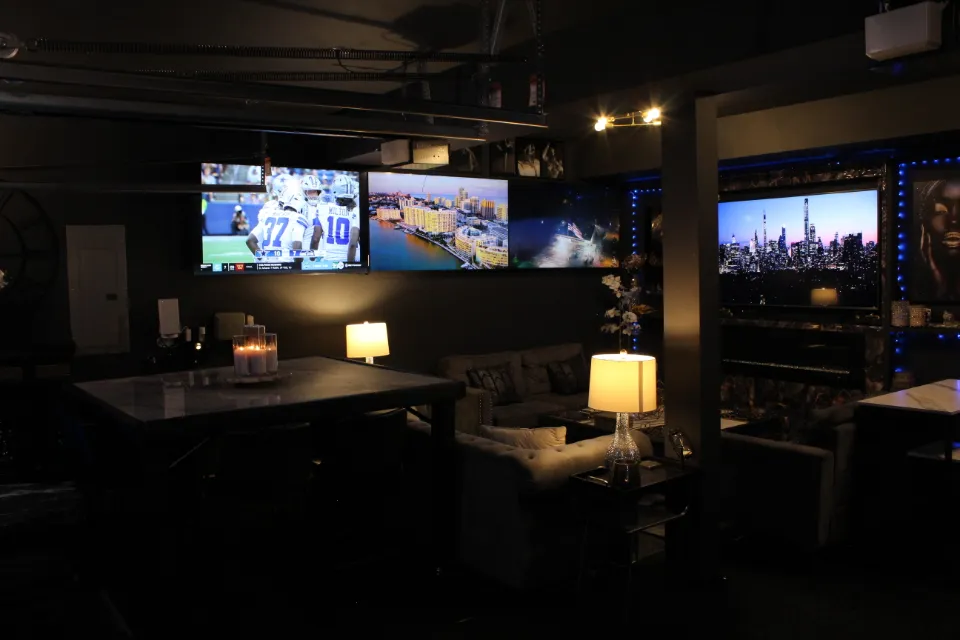 A living room with several screens showing soccer games, a view of a city, and a nighttime cityscape.